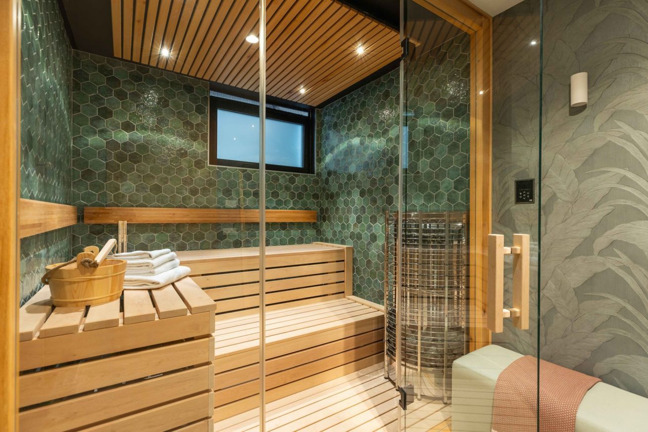 Een sauna met houten banken, een douchecabine van glas en een raam.