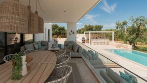 Et moderne udendørs opholdsområde med pool, fletmøbler og en stenvæg.
