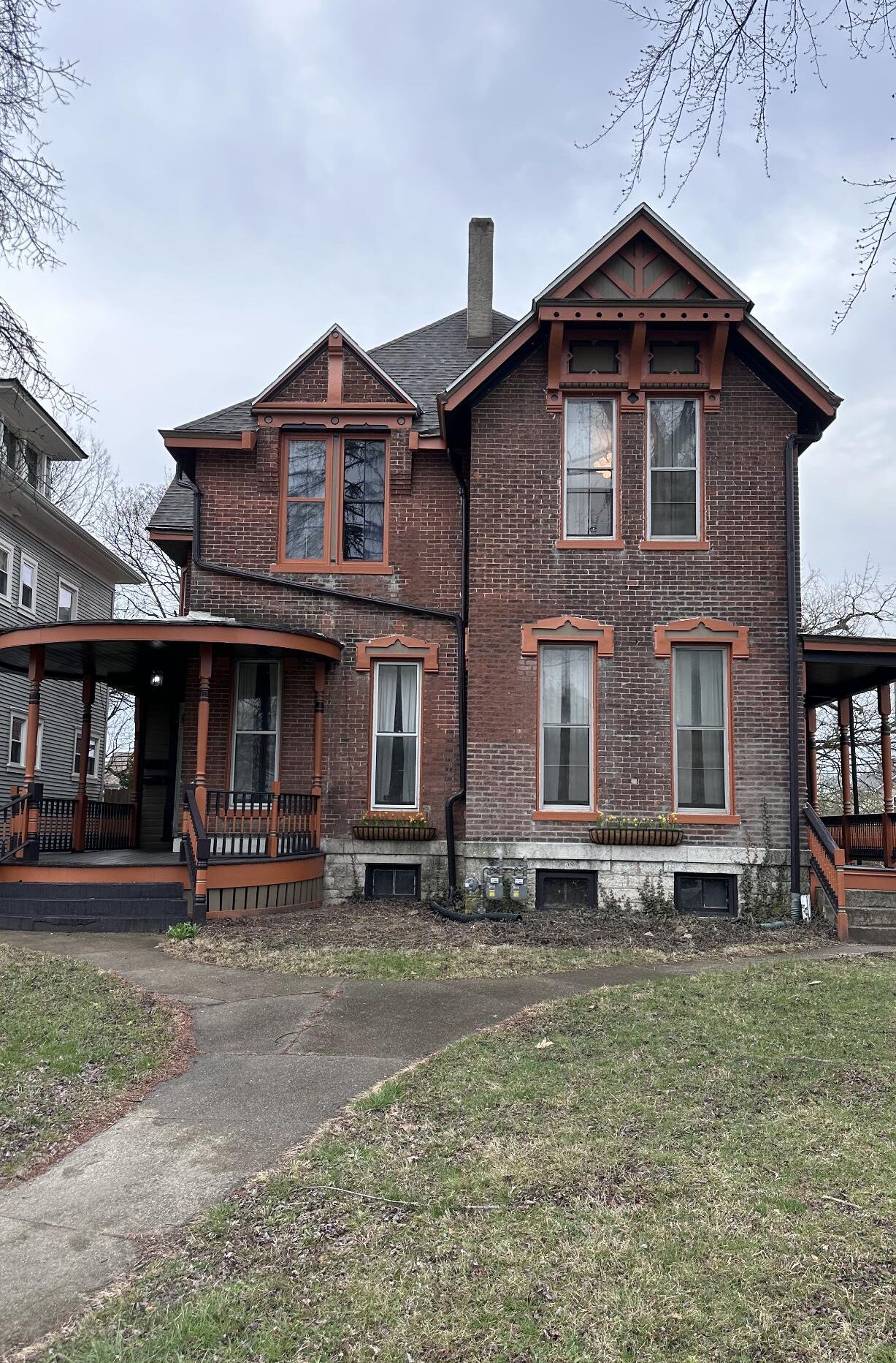A two-story brick house with a porch and a chimney.