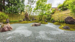 Ein traditioneller japanischer Garten mit Kiesweg, großen Felsen und Bambusumzäunung.