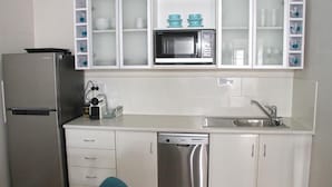 A compact kitchen with a refrigerator, microwave, dishwasher, and a sink.