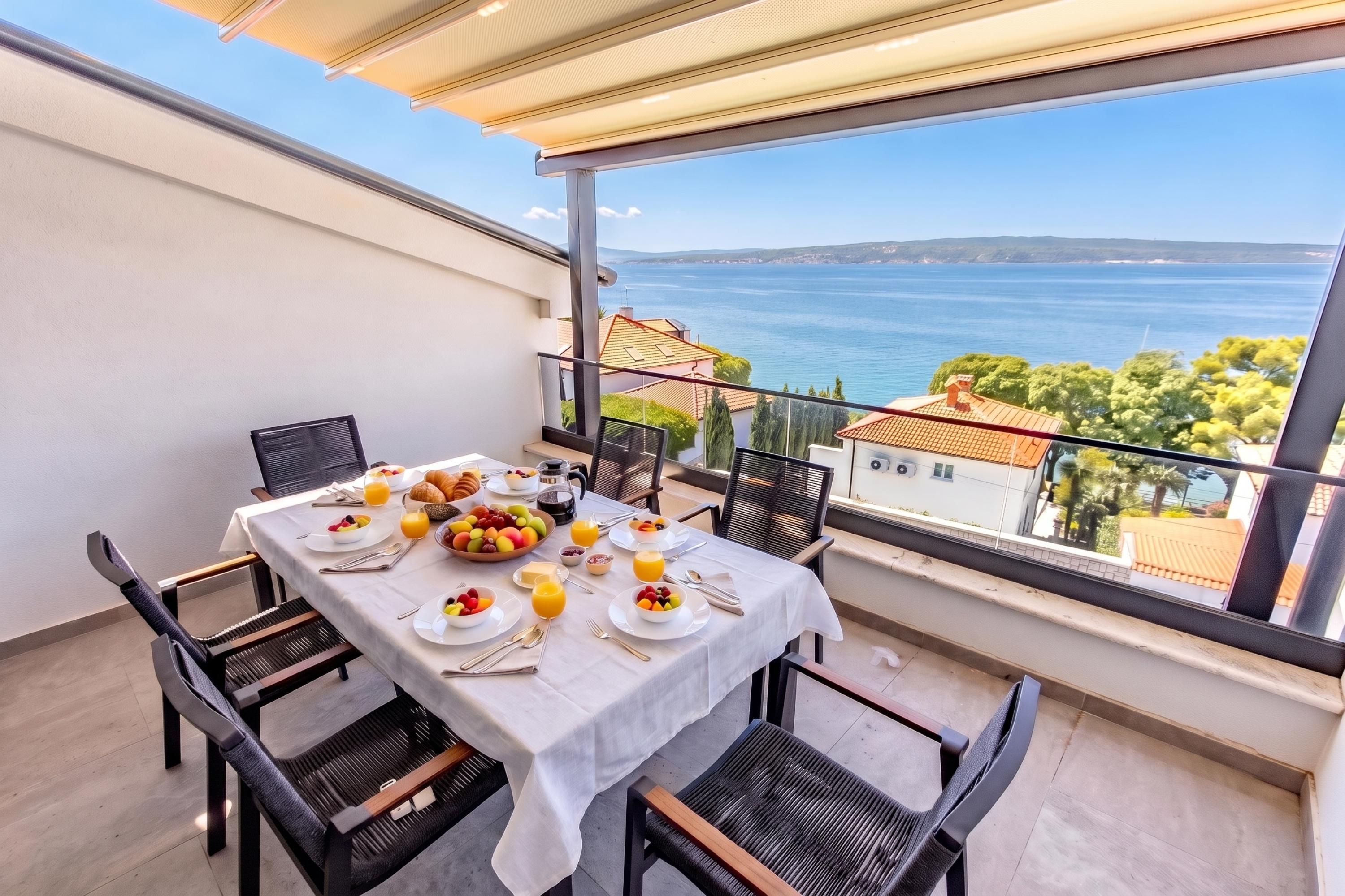 A balcony with a table set for breakfast, overlooking a coastal view.