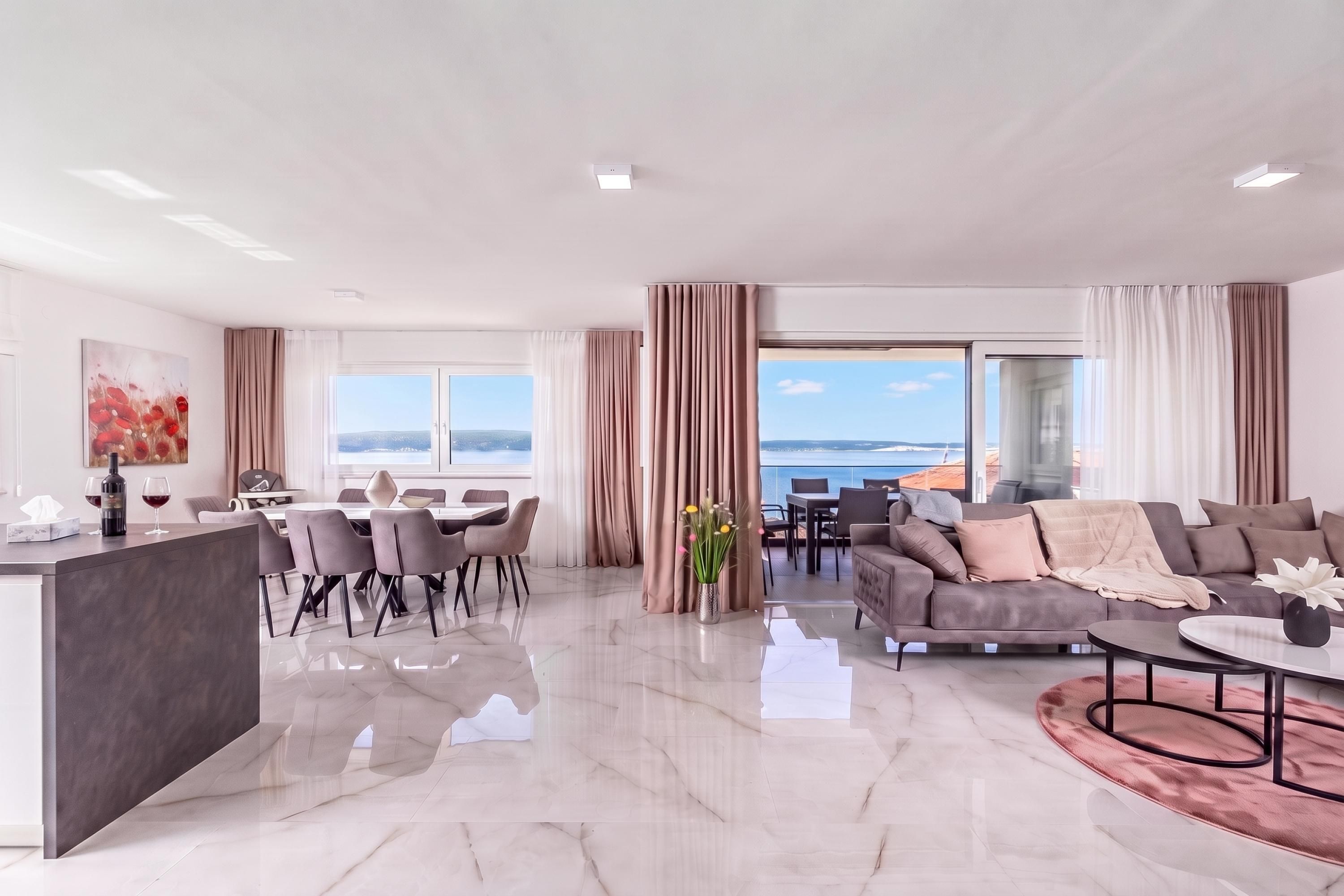 A spacious living area with a dining set, a sofa, and a view of the sea.