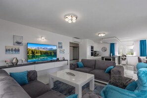 A modern living room with a flat-screen TV, grey sofas, a coffee table, and a kitchen area in the background. - Luxury Pool Apartment With Sea View, Crikvenica, Croatia (Crikvenica)