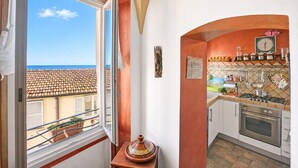 A kitchen with a view of the sea, a window, and a tiled backsplash.