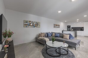 Relax in this stylish living room with a comfortable sofa, flat-screen TV, and kitchen area.