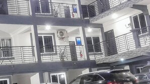 Un edificio de varios pisos con balcones, una unidad central de aire acondicionado y un extintor.