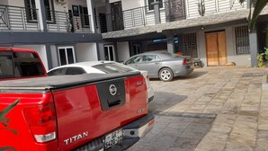 Una camioneta roja Nissan Titan estacionada en un patio, con un sedán gris al fondo.