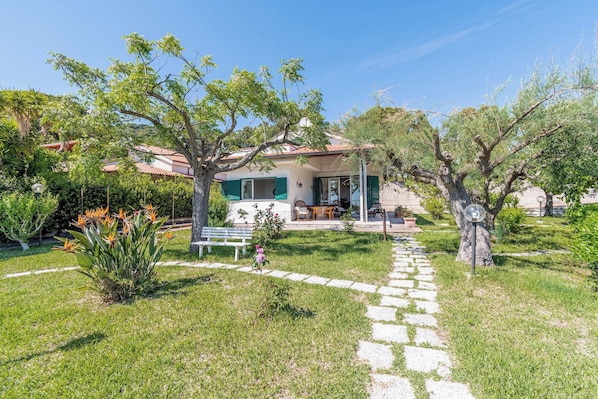 A house with a garden, a pathway, and a bench.