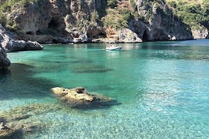 A clear coastal area with rocky terrain and a boat in the water.