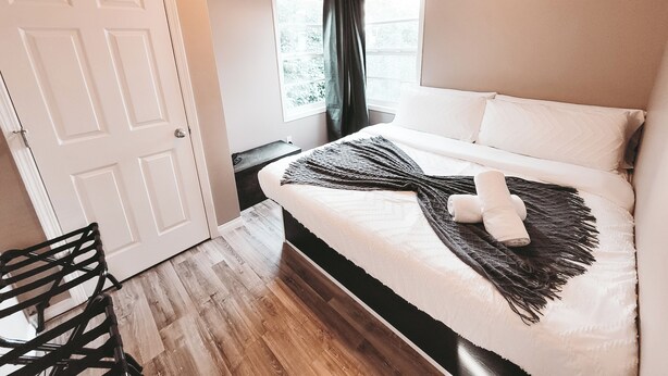 Una camera da letto con un letto, una sedia, una finestra e una porta.