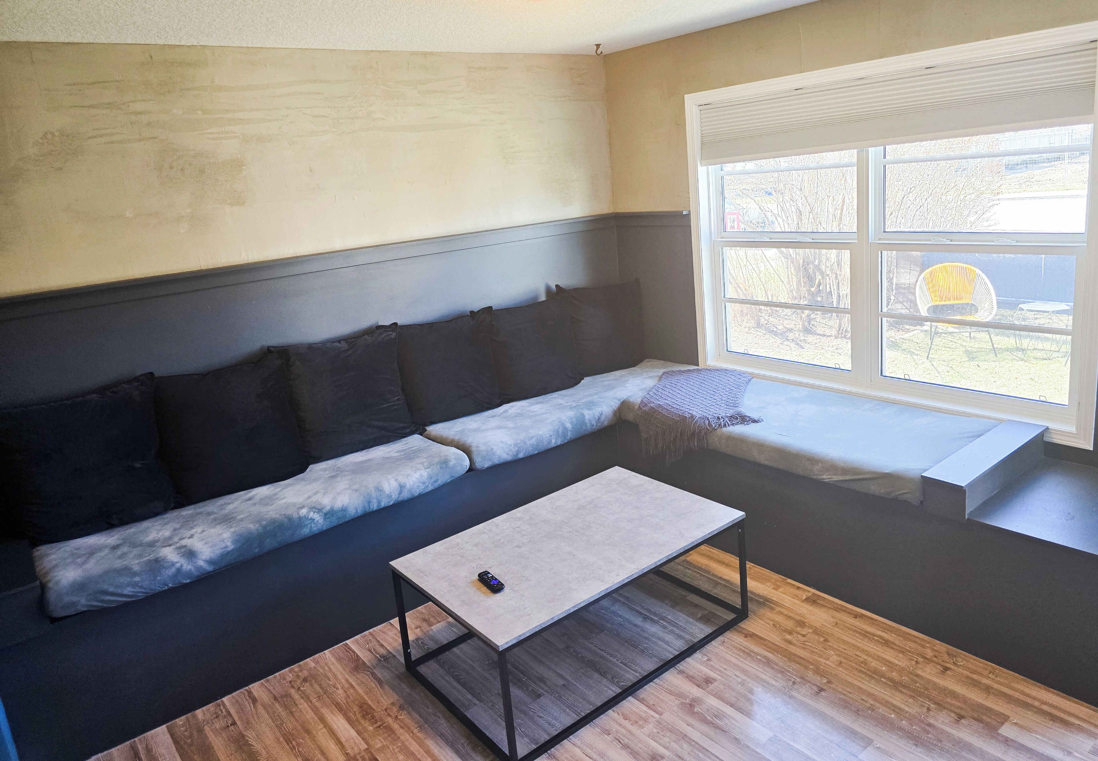A modern living room with a sectional sofa, a coffee table, and a large window with a view of the outdoors.
