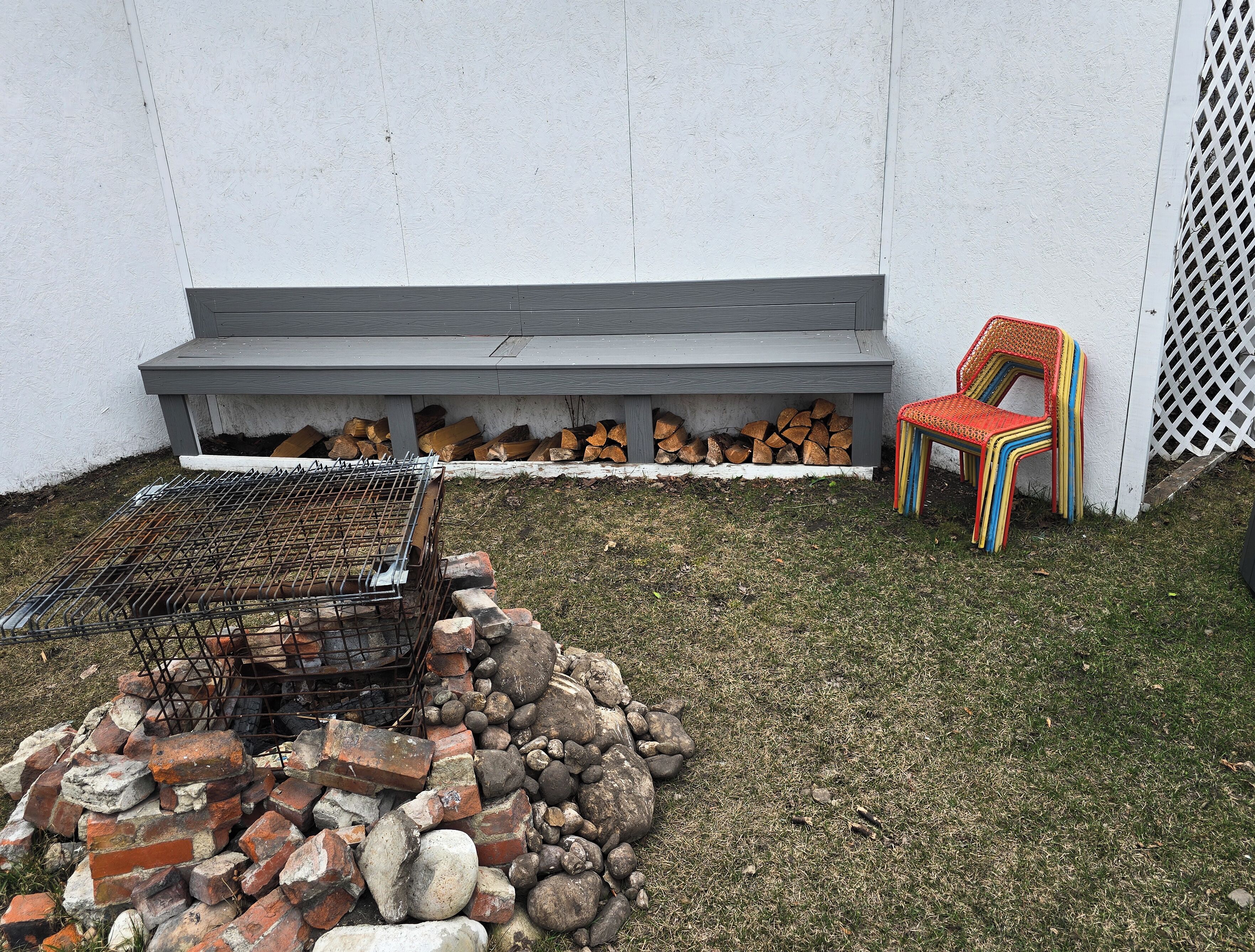 Patio trasero con una parrilla, un pozo de fuego y sillas de colores.