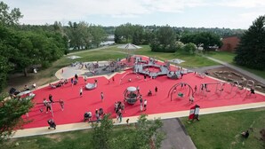 Un'area giochi con pavimentazione rossa, altalene e strutture per arrampicarsi.