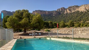 A swimming pool with clear water, surrounded by a fence, and a view of mountains in the background. - Cortijo el Corralon Castril, casa 1, casa 2 (Castril)