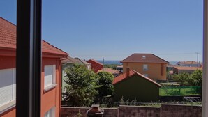 Un barrio residencial con casas, cielo despejado y una vista distante del mar.