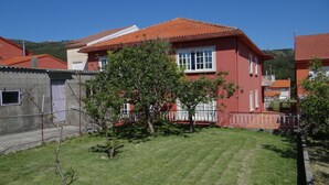 Una casa roja con techo de tejas, rodeada de un césped cuidado y un pequeño árbol.
