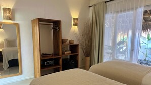 A bedroom with two beds, a wooden wardrobe, a mirror, and a window with curtains. - Sol Villas Gili Air  (Gili Air)