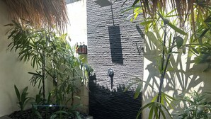 A small, enclosed garden area with a stone wall, a water feature, and various plants. - Sol Villas Gili Air  (Gili Air)