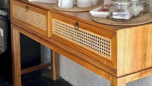 A wooden counter with white ceramic cups, a tea set, and glass jars on woven placemats. - Sol Villas Gili Air  (Gili Air)