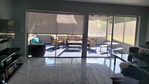 A modern living room with a large sliding glass door leading to an outdoor patio area. - Cozy 3-bedroom house in peaceful Spring Hill with WiFi, AC. Sleeps up to 15 (Spring Hill)