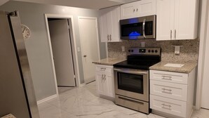 A modern kitchen with white cabinets, a stainless steel refrigerator, a microwave, a stove, and a dishwasher. - Cozy 3-bedroom house in peaceful Spring Hill with WiFi, AC. Sleeps up to 15 (Spring Hill)
