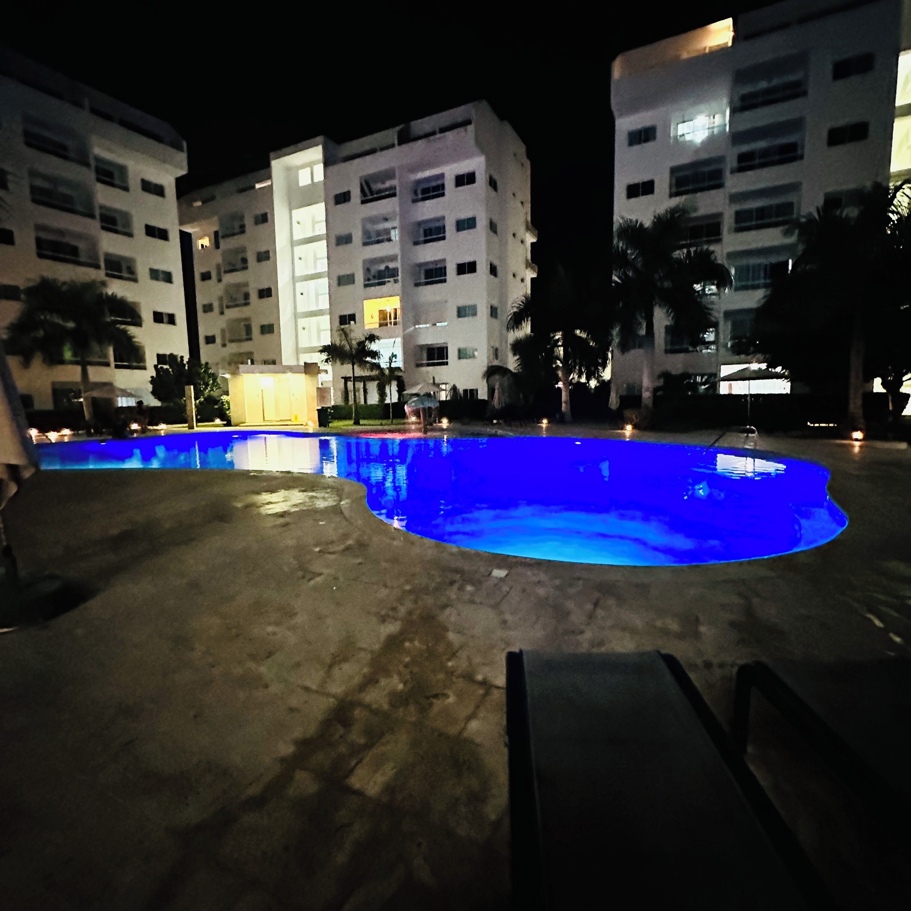 Una piscina de borde curvo, rodeada por una solana de hormigón.