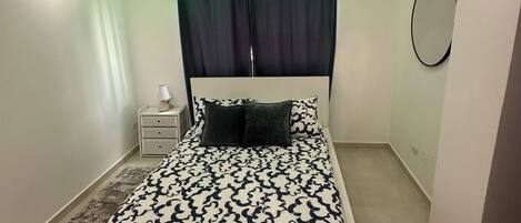 Un dormitorio moderno con una cama grande, una mesita de noche, una lámpara y un espejo en la pared.
