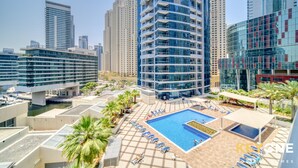 Un hotel moderno con piscina en la azotea, edificios altos y cielo despejado.