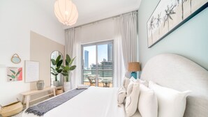 Una habitación de hotel moderna con una cama grande, un balcón con vista a edificios altos y un paisaje urbano.