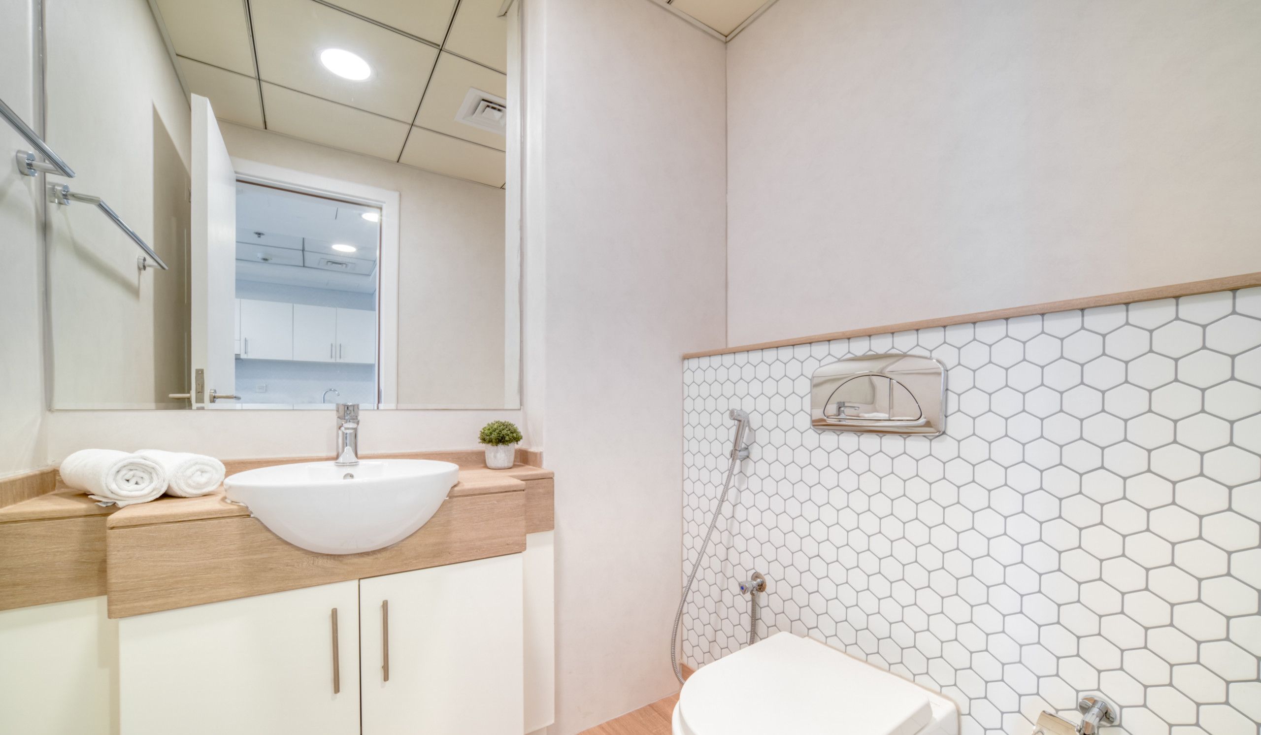 A modern bathroom with a white sink, wooden countertop, and a hexagonal tile backsplash.