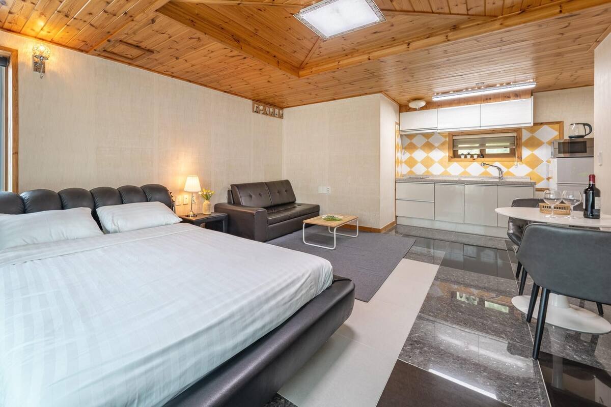 Une chambre avec un grand lit, un canapé, une petite table et une vue sur la mer.