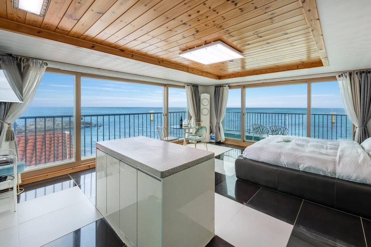 Une chambre moderne dotée d’un grand lit, d’un petit coin cuisine et d’un balcon offrant une vue sur la mer.