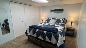 A bedroom with a bed, two bedside lamps, a wall clock, and a mirror. - Cozy 1 bedroom apartment in Enjoyable Ketchikan with WiFi.  (Ketchikan)