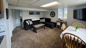 A compact living space with a sofa, a small table, a TV, and a window. - Cozy 1 bedroom apartment in Enjoyable Ketchikan with WiFi.  (Ketchikan)