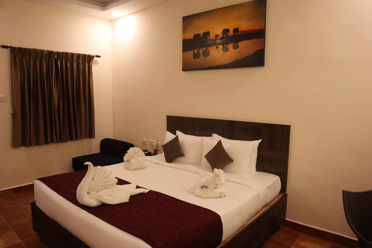 A hotel room with a large bed, a headboard, a painting on the wall, and a curtain.