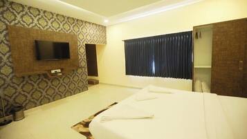 A hotel room with a bed, a TV mounted on the wall, a wardrobe, and a window with curtains.