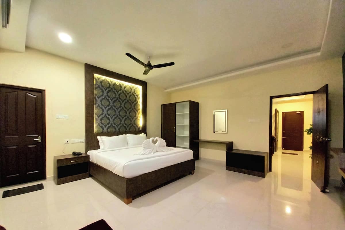 A modern hotel room with a large bed, a ceiling fan, a nightstand, a dresser, and a mirror.