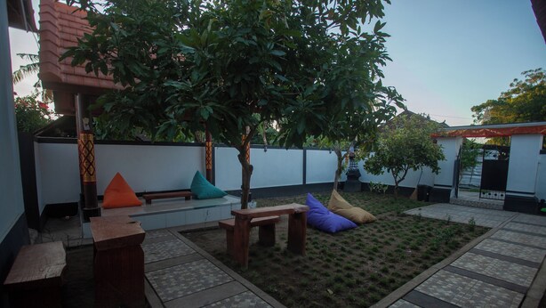 A courtyard with a seating area, a small tree, and a tiled floor.