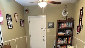 A cozy living room with a wooden floor, a patterned rug, a bookshelf, a chair, and a sofa.