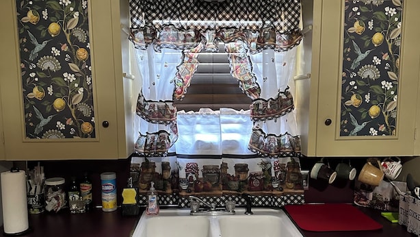 A kitchen with a central island, a double sink, and a stove.