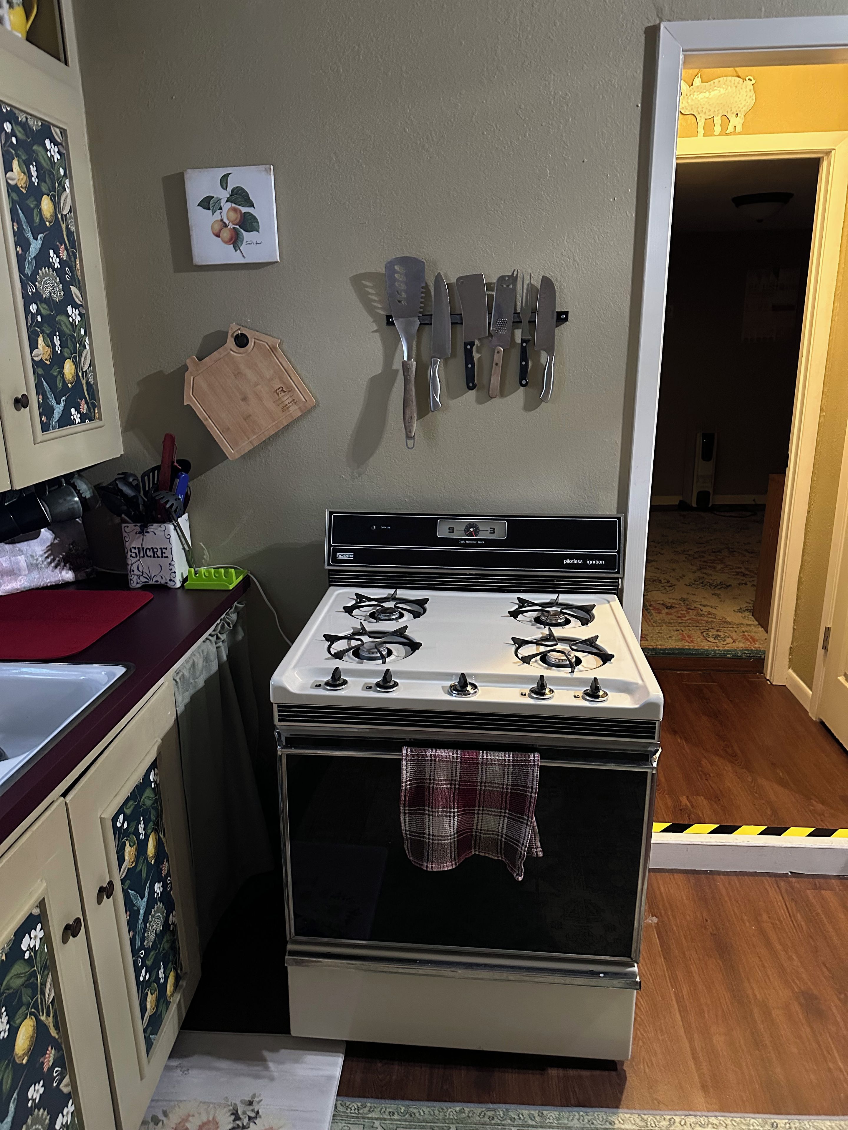 Une cuisine équipée d’une cuisinière, de couteaux et d’un meuble décoré sur le thème des fruits.