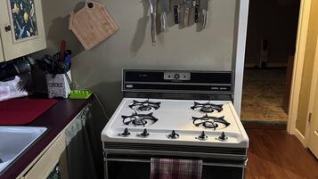 Une cuisine équipée d’une cuisinière, de couteaux et d’un meuble décoré sur le thème des fruits.