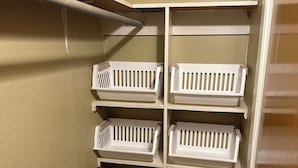 A storage closet with wooden flooring and white shelves.