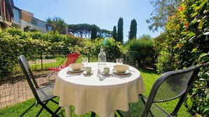 A round table with a white tablecloth, two chairs, and a bottle of water.