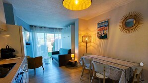 A modern kitchen with a dining area, a sofa, and a table with chairs.