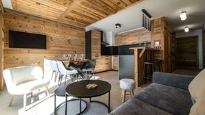 Een modern interieur met een houten plafond, een eethoek met tafel en stoelen, een bank en een keuken met kastjes en een aanrecht.