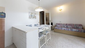 Een compacte woonruimte met een kitchenette, een eethoek en een slaapbank.