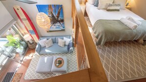 A hotel room with a bed, a sofa, a dining area, and a large window.
