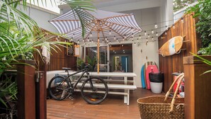 A wooden deck with a bicycle, a picnic table, and surfboards.